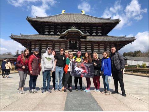 A photo a group of people posing in front of a building with an "Indiana University East" flag.