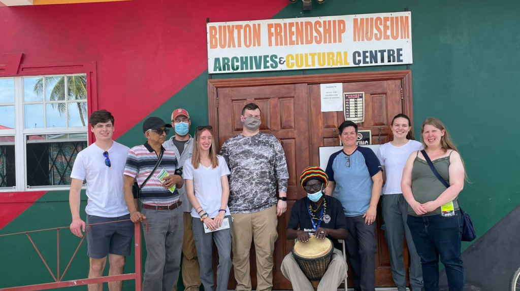 A group of people standing next to a person with a drum.