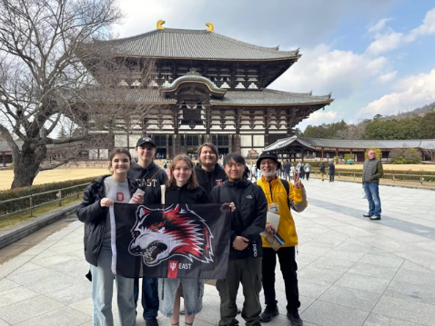 A photo of a group of people posing in front of a building.