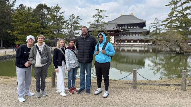 A photo of a group of people posing in front of a pond.