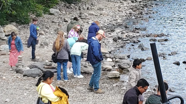 A photo of a group of people collecting rocks off of the Loch Ness shoreline.