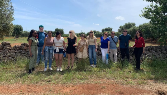 A photo of a group of people posing in front of a stone wall.