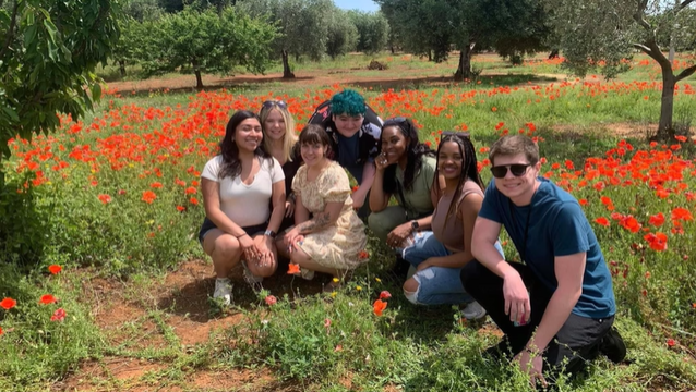 A photo of a group of people posing in a field of flowers.