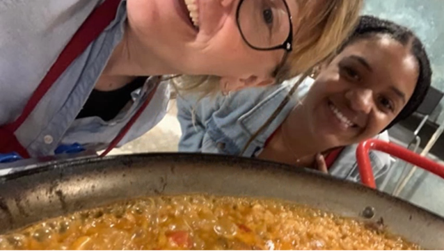 A photo of two people posing for a selfie over a pan of Paella.