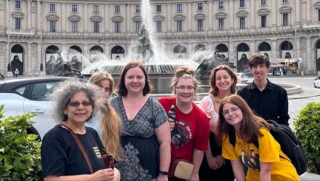 A photo of a group of people in front of a fountain.