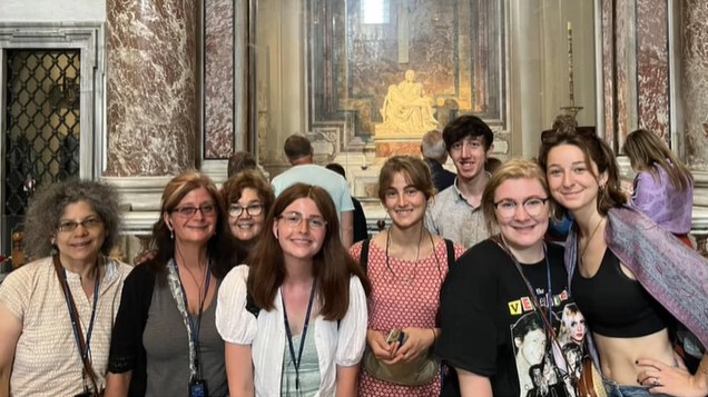 A photo of a group of people posing in front of a statue.