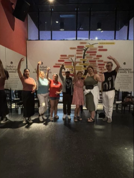 A photo of a group of people posing in front of a sign.