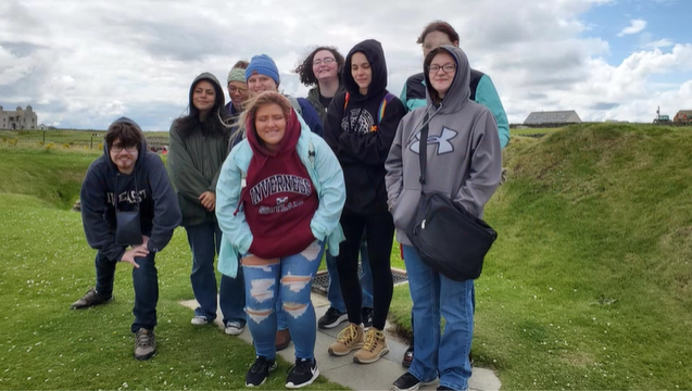 A photo of nine people posing in a grassy field.