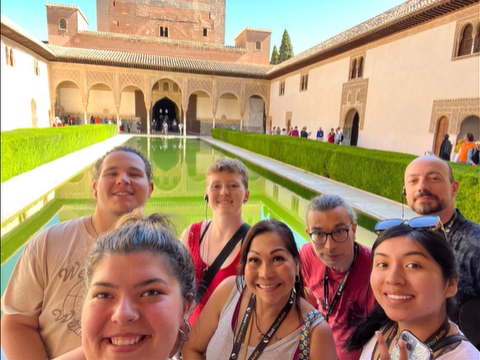 A photo of a group of people posing for a selfie in front of a pond.