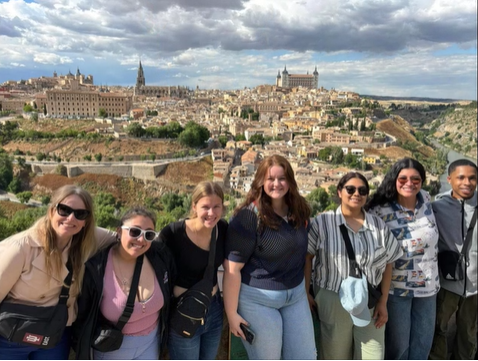 A photo of a group of people posing with a city in the background.