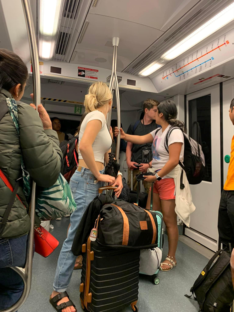 Image of people on the metro with luggage.