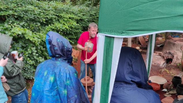 A photo of students watching a potter make a bowl.