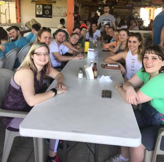 Image of a group of people sitting at a table posing for a photo.