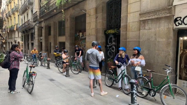 A photo of a group of people standing next to bikes.