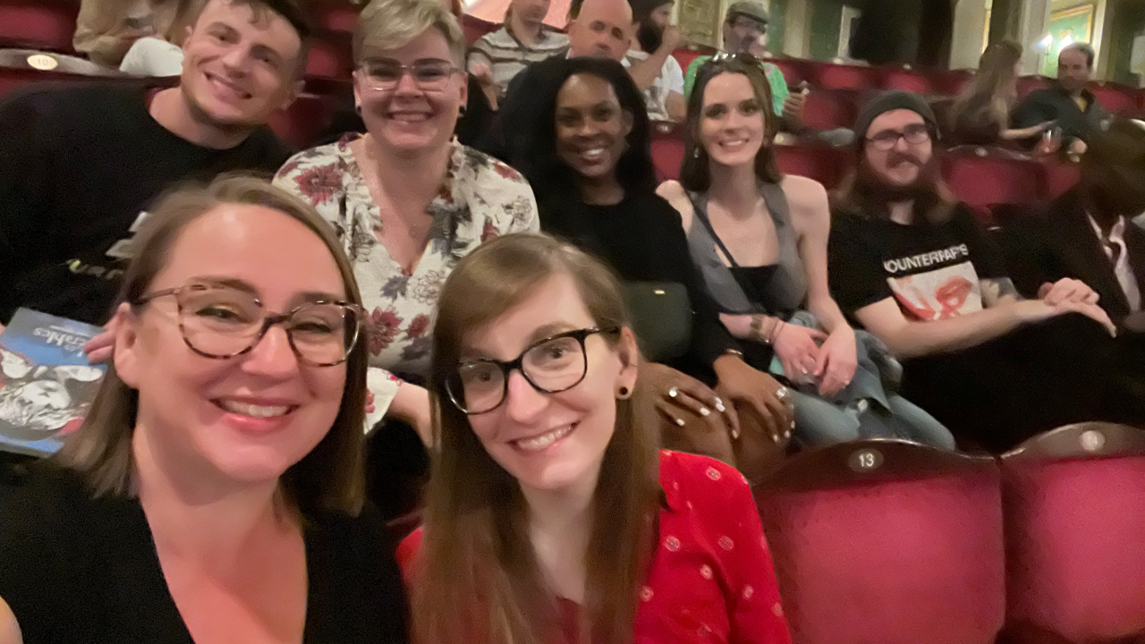 A photo of a group of people posing in a theater.