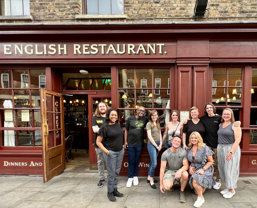 A photo of a group of people posing outside of an English restaurant.