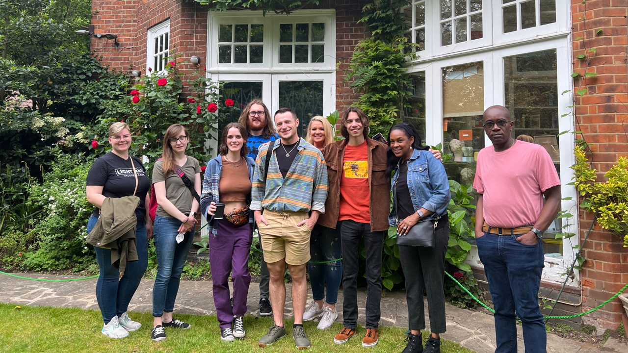 A photo of a group of people posing outside a house.