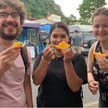 A photo of three people holding fruit.