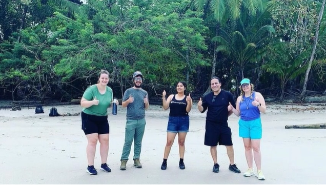 A photo of a group of people posing on a beach.