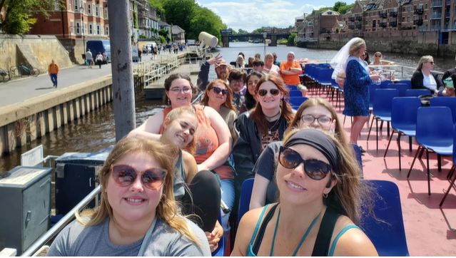 A photo of people posing for a selfie while seated on a boat.