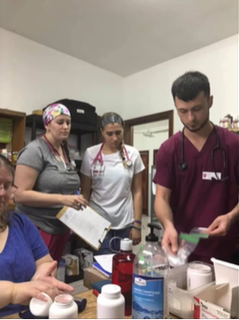 A photo of four people standing over a table of medical supplies.