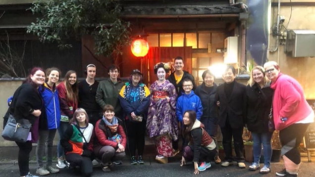 A photo of a group of people posing with a geisha.