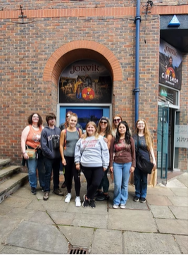 A photo of nine people standing in front of a building.