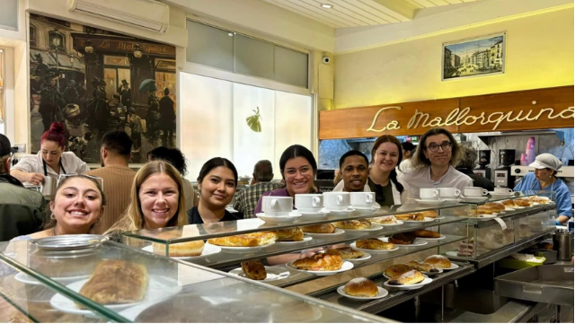 A photo of a group of people posing in front of a coffee bar.