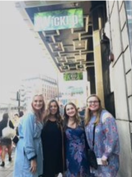 A photo of four people posing outside a theater.