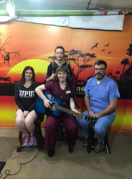 A photo of a group of people posing with a guitar.