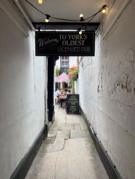 A photo of an alleyway with a sign reading "Welcome to York's oldest licensed pub".