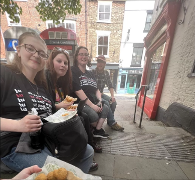 A photo of four people sitting on stairs and eating.