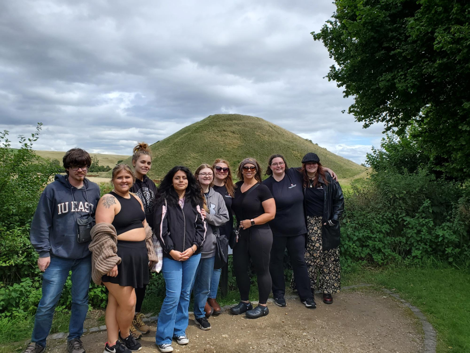 A group of people posing in front of a hill.