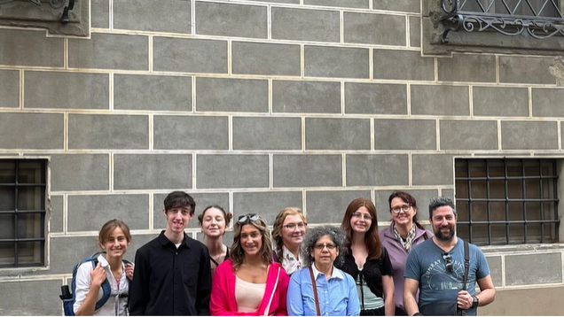 A photo of a group of people standing in front of a wall.