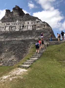 A photo of a group of people climbing Mayan ruins.