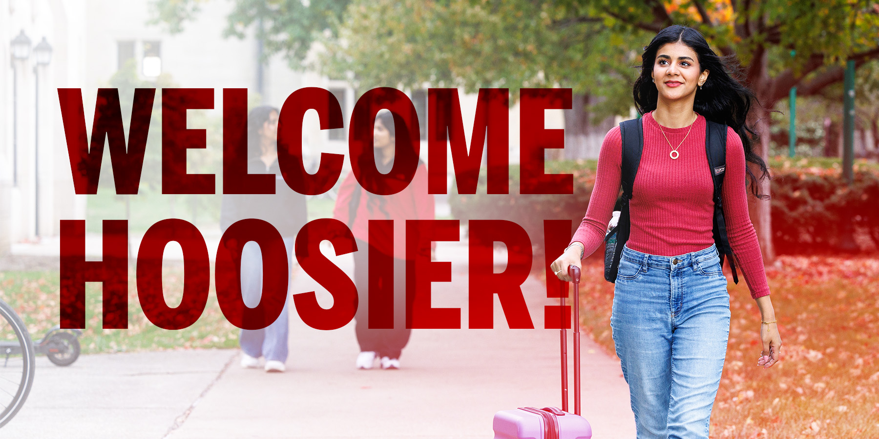 Incoming Student with suitcase walking on campus.