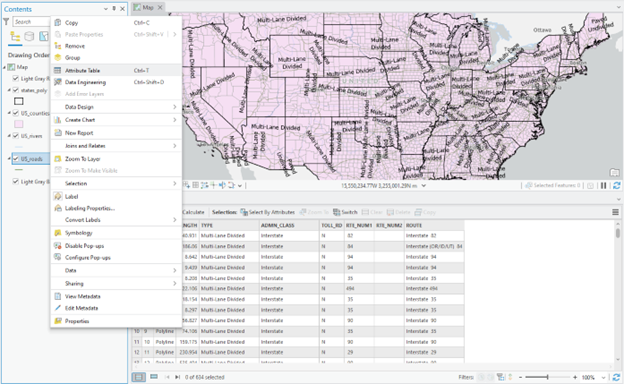 Screenshot of a GIS software interface showing a map of the United States with major highways labeled "Multi-Lane Divided" in pink. Below the map is a data table with columns for Type, Admin Class, Toll Road, Route Number, and Route Name. The left sidebar includes tools for data management and visualization such as Copy, Paste, Attribute Table, Create Chart, Labeling Properties, Symbology, and Configure Pop-ups.