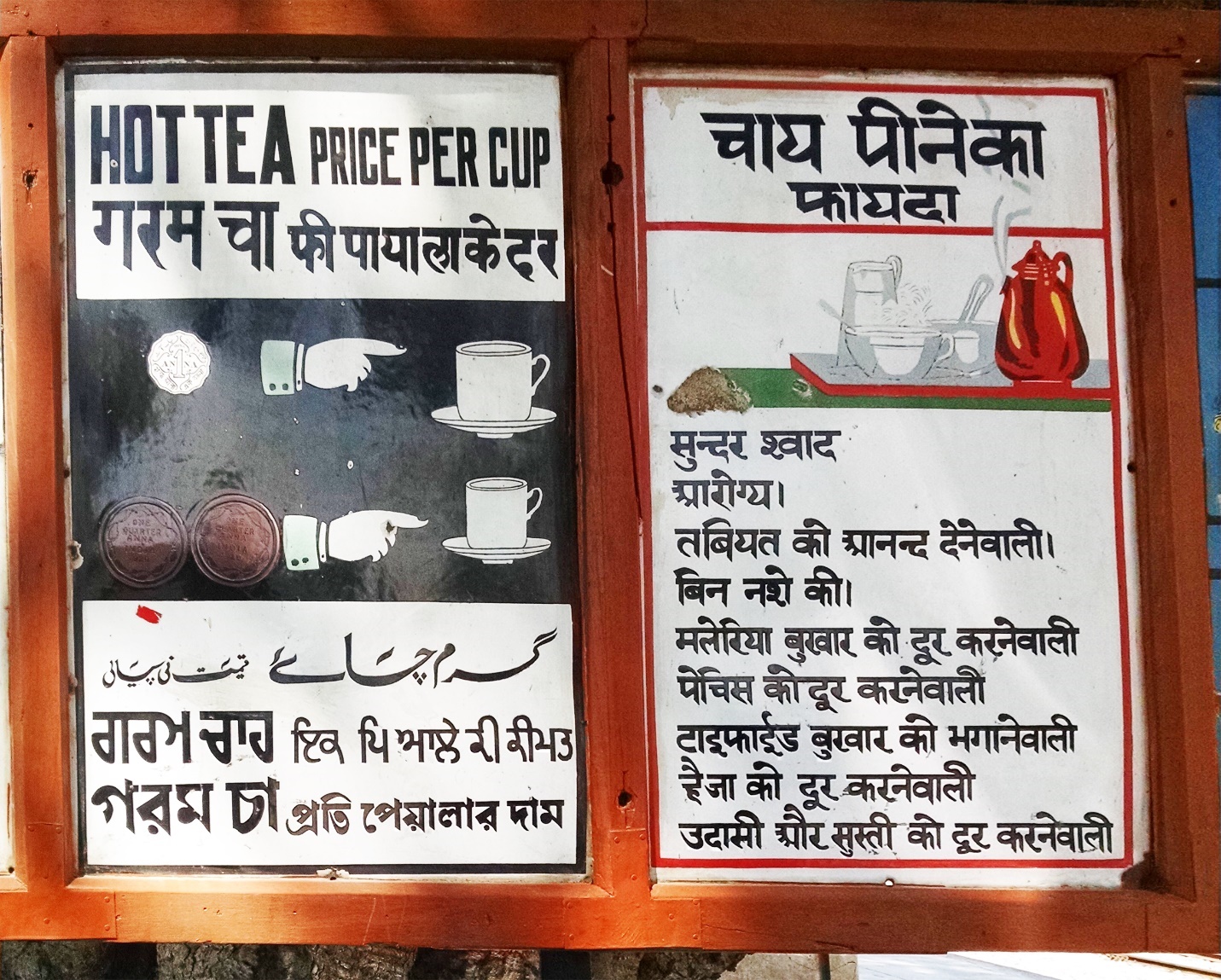 Alt text: A sign on a wooden board with two halves. The left side includes a diagram showing the price of tea represented by coins (one silver coin for a large cup and two copper coins for a small cup) as well as text in five languages indicating “price per cup.” The right side of the sign has a tea tray with teapot and cups and text in Hindi describing the benefits of drinking tea.