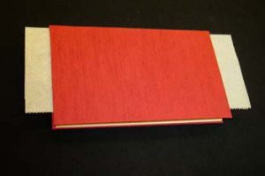 Book with one set of hinges glued down and waxed paper barrier