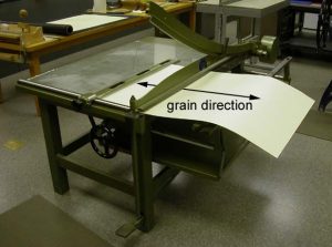 20 pt. board being cut on the board shear, cut being made is perpendicular to the grain direction