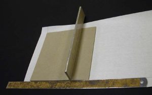 Using a straight edge to align the pieces of board on the cloth for the box cover