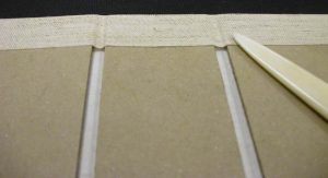 Close up of using a bone folder to smooth them down and make the creases at the joints