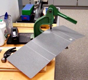 Pulling the handle of the rivet bucker down to press the rivet pieces together