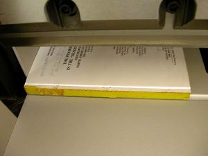 Text block of adhesive bound book in the guillotine