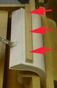 Adhesive is applied with a brush as the text block pages are fanned left