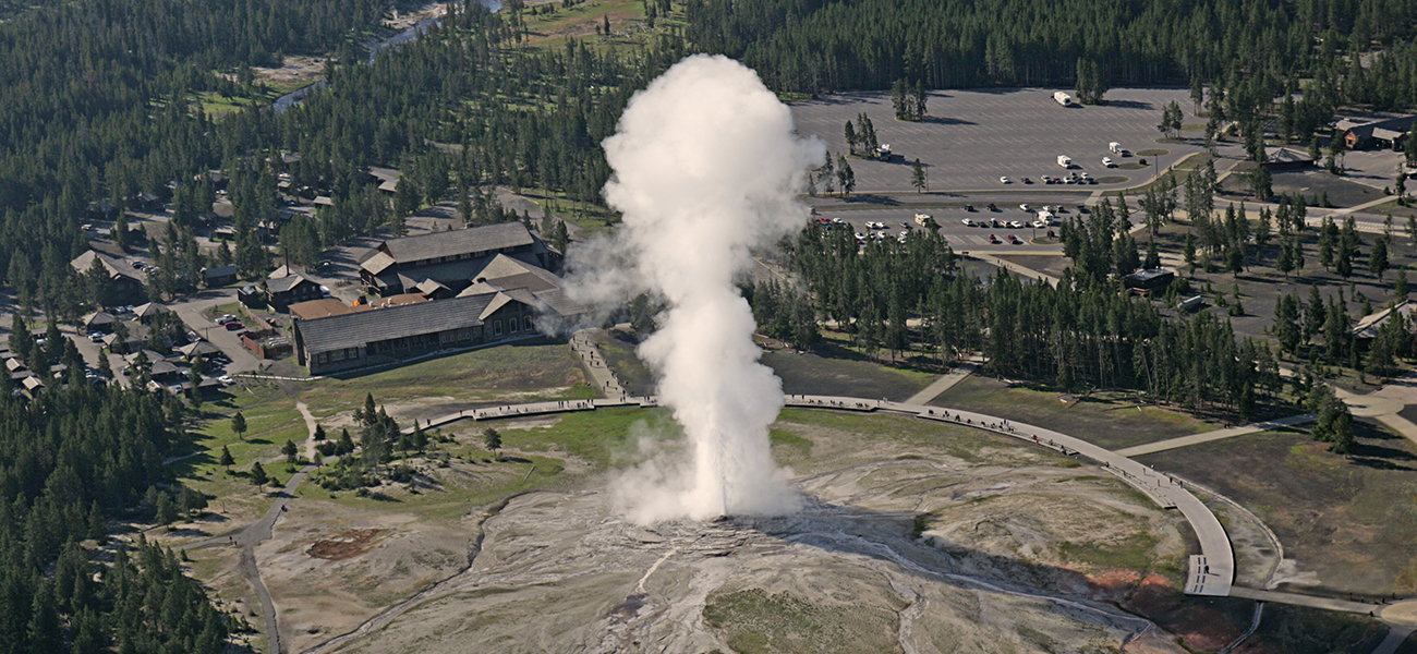 A photograph shows an aerial view of buildings, trees and a large area clear of vegetation, above which rises a plume of steam.