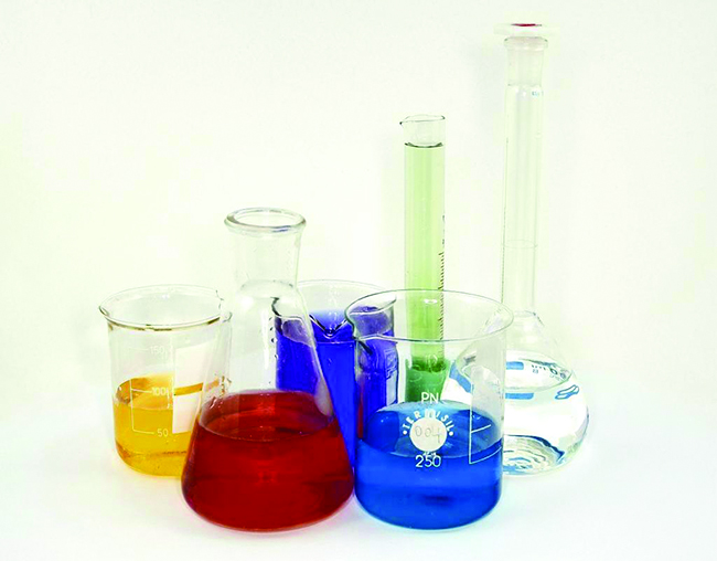 A photo of beakers, flasks, and graduated cylinders is shown. Each piece of glassware holds a different color liquid.