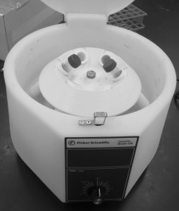 A centrifuge. There is a rotor with six test tube holes in it. The centrifuge has two tubes placed directly opposite each other
