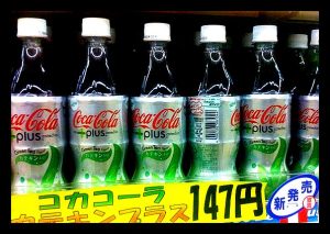 Several Coca-Cola bottles in a freezer case.