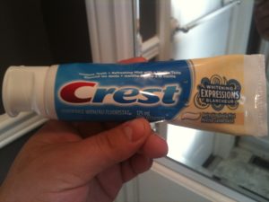 A tube of Crest toothpaste being held in a person's hand.